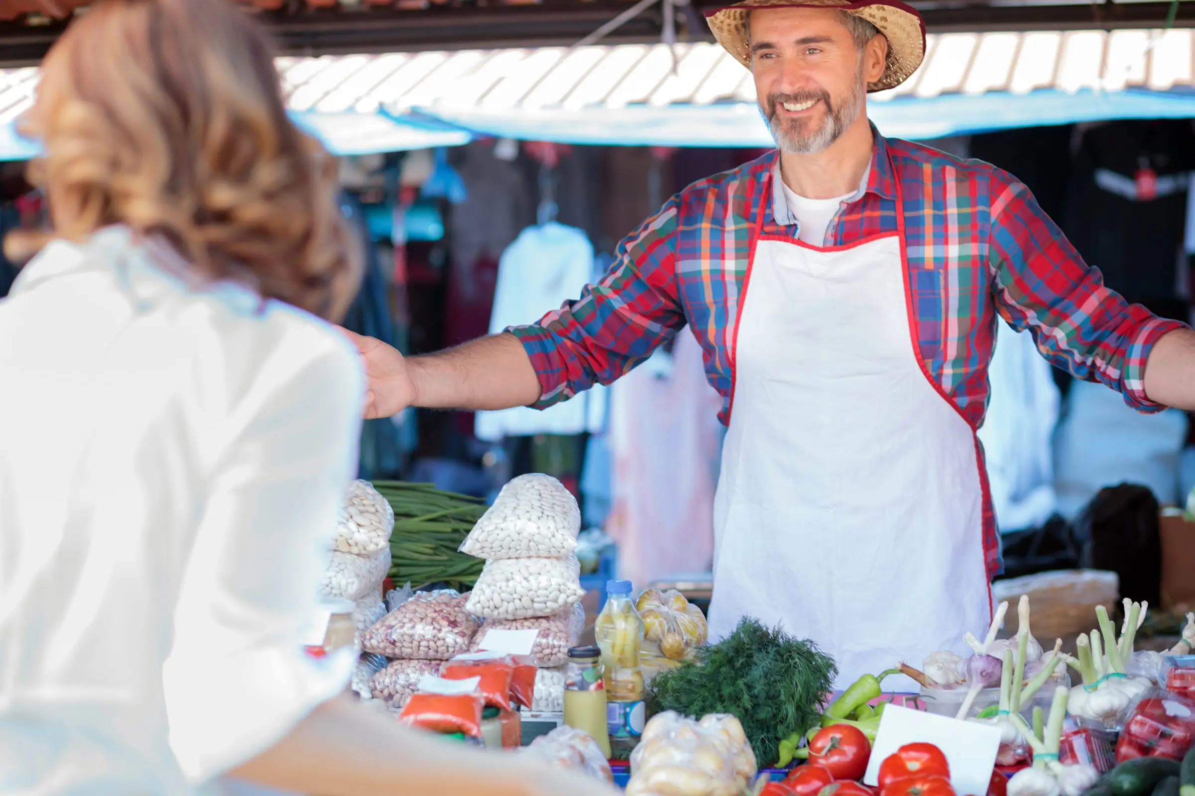 A grower in a straw hat selling vegetables at a local market